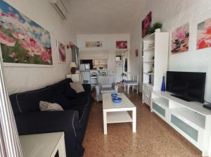 a living room with a couch and a tv and a table at lovely bungalow with parking in Playa del Ingles