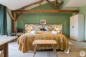 a bedroom with a large bed and a chair at La Ferme des Hautins - Chambres -d'Hôtes in Rieucazé