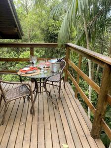 una mesa y sillas en una terraza de madera en Chalé Morada dos Tucanos, en Santo Amaro da Imperatriz
