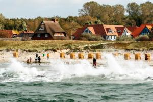 un grupo de personas jugando en las olas en la playa en Oewern Diek 36, en Wustrow