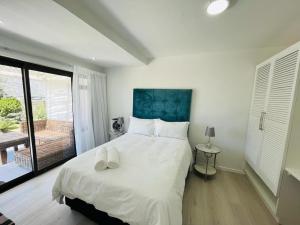 a bedroom with a large white bed and a balcony at Frank Road At The beach in St Francis Bay
