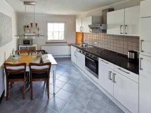 a kitchen with white cabinets and a table with chairs at Dautzenberg Ferienapartments in Bad Neuenahr-Ahrweiler
