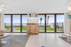a living room with a tv and large windows at Sunrise 109 in New Smyrna Beach