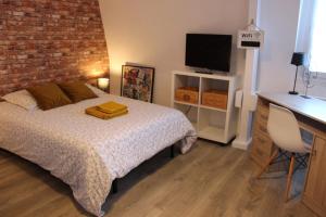 a bedroom with a bed and a desk with a television at Studio 211 au cœur du campus de Belle Beille in Angers