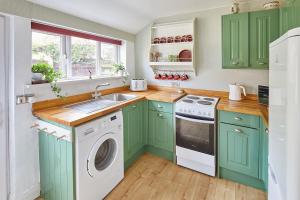 a kitchen with green cabinets and a washing machine at Traditional cottage with brand new Woodburner in Wark
