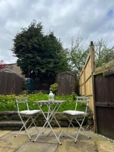 a table and two chairs in a yard with a fence at Traditional cottage with brand new Woodburner in Wark