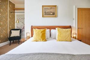 a bedroom with a large white bed with yellow pillows at Traditional cottage with brand new Woodburner in Wark +4 photos