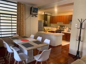 a kitchen with a table and some white chairs at Casa Hospedaje Las Lomas con piscina en La Merced in La Merced