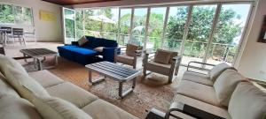 a living room with couches and chairs and windows at Summit View Guest House in Los Altos de Cerro Azul +2 photos