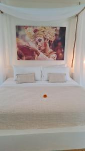 a white bed with a large picture on the wall at Guru Canggu in Canggu