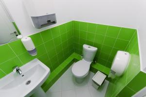 Baño de azulejos verdes con aseo y lavamanos en Maxi House Hostel en Rostov-on-Don