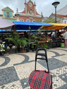 una maleta sentada en el suelo frente a un mercado en JScAsa Rainha Centro, en Caldas da Rainha