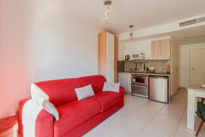 a red couch in a living room with a kitchen at Krystal Palace - Luxe & Vue Mer, Aux Portes de Monaco in Beausoleil