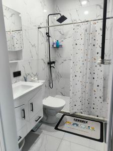 a white bathroom with a shower curtain and a toilet at Willy's House in Batumi