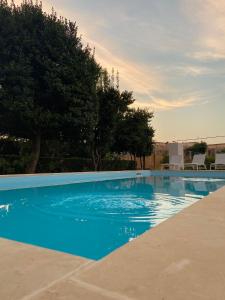 una piscina blu con alberi sullo sfondo di Villa De Pietro a Cursi