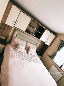 a bedroom with a large white bed with pillows at Metcalfes family caravan in Heysham +25 photos