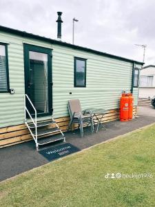 a house with two chairs and a table in front of it at Metcalfes family caravan in Heysham