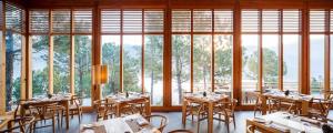 a dining room with tables and chairs and windows at Dhensa Resort in Punākha
