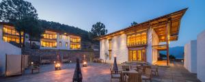 an outdoor patio with tables and chairs and a building at Dhensa Resort in Punākha