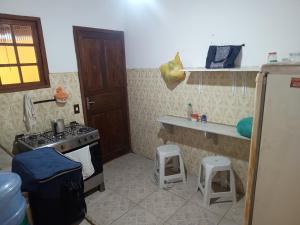 una cocina con fogones y 2 taburetes. en Casa temporada em Rio das Ostras, en Rio das Ostras