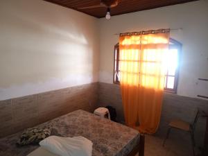 1 dormitorio con 1 cama y una ventana con cortina naranja en Casa temporada em Rio das Ostras, en Rio das Ostras