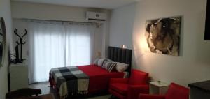 a bedroom with a bed and a red chair at Mendoza 1638 Aparments in Rosario