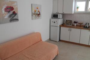 a kitchen with a couch and a white refrigerator at Adria Apartments in Podgora
