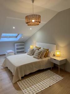 a bedroom with a large bed and a chandelier at Ático Deluxe muy cerca de la playa, Parking gratis in Moaña