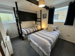 a bedroom with two beds and two windows at Malt-Barn Conversion, with access to Pool & Hot Tub-at Fox Valley Cottages in Lansallos +30 photos