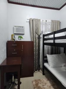 a bedroom with a desk and a bunk bed with a computer at Goldland Caelestis Guest House in Bacolod