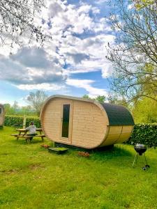 duża drewniana przyczepa siedząca w trawie obok stołu piknikowego w obiekcie Camping Les Voiles Sur Grosne w mieście Savigny-sur-Grosne