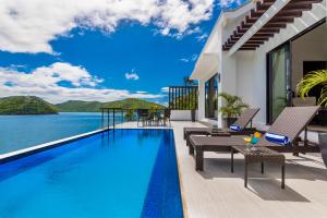 a villa with a swimming pool with a view of the ocean at Busuanga Bay Lodge in Busuanga