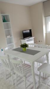 Biały stół jadalny z białymi krzesłami i telewizor w obiekcie Apartamentos Dunamar w mieście Noalla