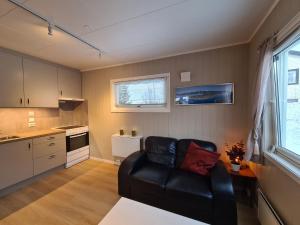 a living room with a black leather couch in a kitchen at Studio Apartment in Tromsø in Tromsø