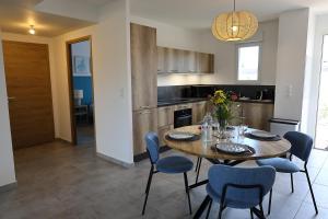 a kitchen with a wooden table and blue chairs at Villa Tranquille - Maison 4 étoiles 2 Chambres Bonifacio in Bonifacio