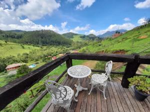 einen Tisch und Stühle auf einer Holzterrasse mit Aussicht in der Unterkunft Paraíso da serra visconde de Mauá in Visconde De Maua