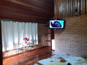ein Wohnzimmer mit einem TV an einer Backsteinwand in der Unterkunft Paraíso da serra visconde de Mauá in Visconde De Maua