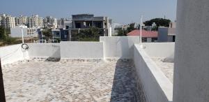 a balcony with white walls and a view of a city at Nest Homestays in Jamnagar