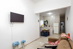 ein Wohnzimmer mit einem Sofa und einem Fernseher an der Wand in der Unterkunft Casa de condomínio HP2 - Ideal para turistas e empresas - 7 min de carro das praias Tupi e Ocian in Praia Grande