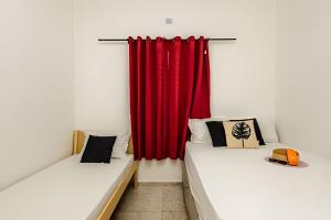 2 Betten in einem Zimmer mit einem roten Vorhang in der Unterkunft Casa de condomínio HP2 - Ideal para turistas e empresas - 7 min de carro das praias Tupi e Ocian in Praia Grande