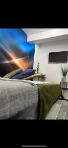 a bedroom with a large bed with a painting on the wall at O5 residence in Nivy
