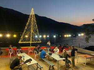 een groep mensen die aan tafels voor een kerstboom zitten bij Mekong backpackers 2 in Pakbeng