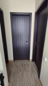 a hallway with a black door and a wooden floor at bakuriani in Bakuriani +1 photo