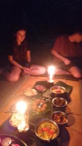 a group of people sitting on the floor with lit candles at Pongo Guest House & only jungle trekking whit us in Bukit Lawang