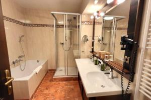 a bathroom with a tub and a sink and a shower at Hotel Batzenhäusl in Innsbruck