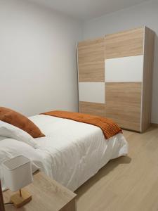 a bedroom with a white bed and a wooden headboard at Apartamentos La Fuente in Almodóvar del Río