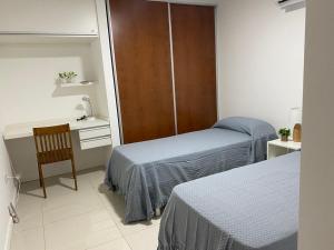 a bedroom with two beds and a desk and a chair at Dpto 9 DE JULIO in Villa María