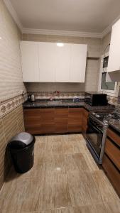 une cuisine avec des armoires blanches et une poubelle noire dans l'établissement Rehab Elegant Apartment - New Cairo, à Burg el-Ḥudûd 17 autres photos