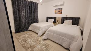 une chambre avec deux lits et une fenêtre dans l'établissement Rehab Elegant Apartment - New Cairo, à Burg el-Ḥudûd