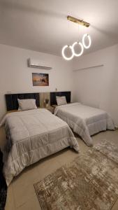 Cette chambre blanche comprend 2 lits. dans l'établissement Rehab Elegant Apartment - New Cairo, à Burg el-Ḥudûd